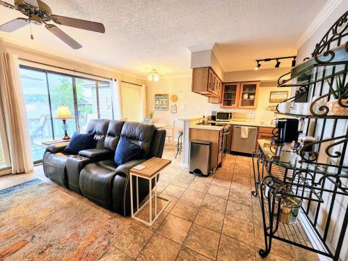 a living room with a leather couch and a kitchen at Farr Shores Cozy Retreat in Red Oak