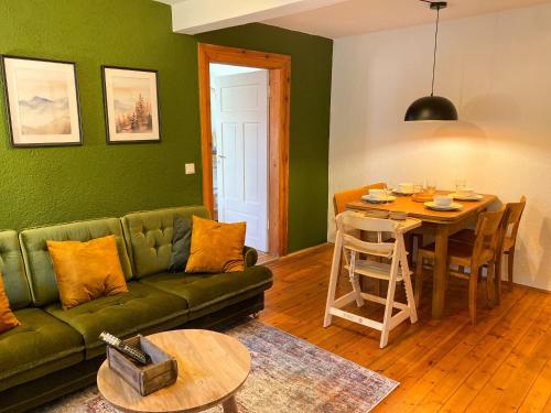 a living room with a green couch and a table at Familien Glück in Gleisweiler