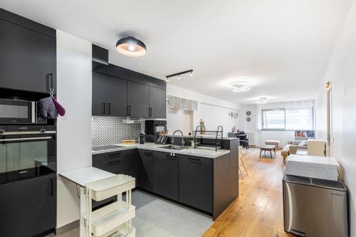 une cuisine avec des armoires noires et un salon dans l'établissement GuestReady - A lovely gem near Paris, à Neuilly-sur-Seine