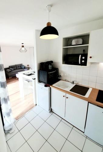 La cuisine est équipée de placards blancs et d'un four micro-ondes noir. dans l'établissement La Frégate studio spacieux avec terrasse, à La Rochelle