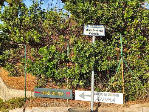 a street sign with several signs in front of a bush at Oriente Dell'Etna in Belpasso