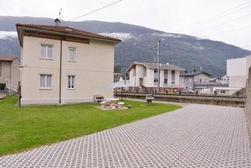 a building with a grass yard next to a house at Miralago Apartments - 8 min Walk to Bernina Express in Tirano