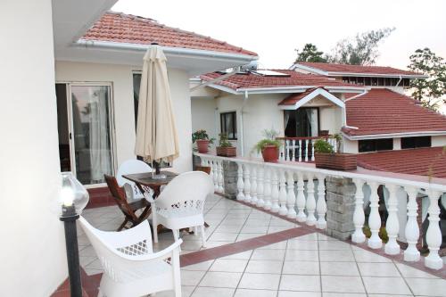 a balcony with a table and chairs and an umbrella at Carana Hilltop Villa Seychelles in Glacis