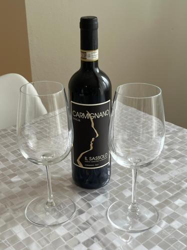a bottle of wine and two wine glasses on a table at Casa nuova a due passi stazione e 20 minuti da Firenze in Empoli