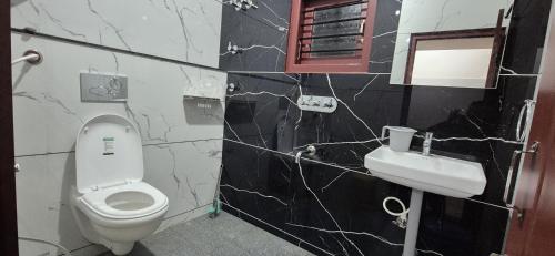 a bathroom with a white toilet and a sink at Chiraanya Service Apartment in Chikmagalūr