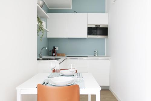 a white kitchen with white cabinets and orange chairs at Gonin 58 in Milan