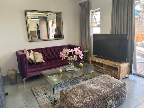 a living room with a purple couch and a tv at Nora's Place in Sedgefield