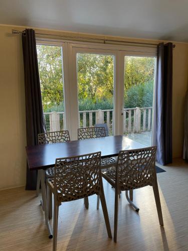 a dining room table with chairs and a large window at Camping Du Perche Bellemois in Bellême