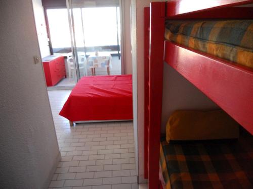 une chambre avec un lit superposé et un couvre-lit rouge dans l'établissement Cap d'Agde Naturiste côté Piscine, au Cap d'Agde