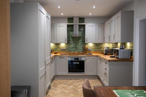 a white kitchen with white cabinets and a table at 2 Bed Ironbridge in Ironbridge