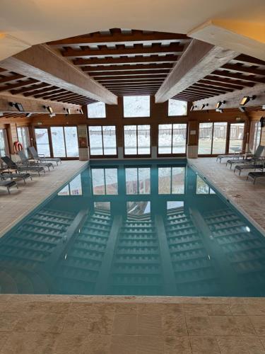 une grande piscine avec des chaises dans un bâtiment dans l'établissement ARC 1950 HAMEAU du GLACIER 306, à Arc 1950