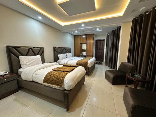 a hotel room with two beds and a chair at Hotel Summer Palace Murree in Murree