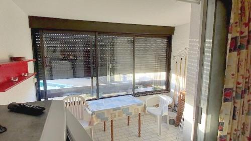 une cuisine avec une table et des chaises ainsi qu'une grande fenêtre dans l'établissement Cap d'Agde Naturiste côté Piscine, au Cap d'Agde