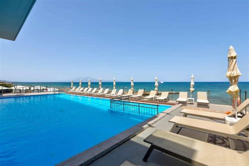 a swimming pool with chairs and the ocean in the background at Amaltheia Beachfront Villas in Kipseli