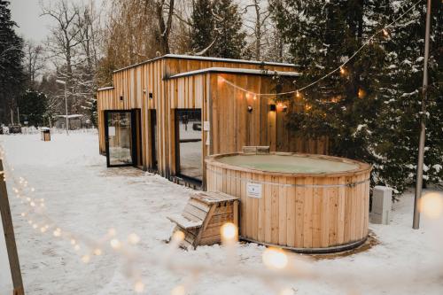 a wooden building with a hot tub in the snow at Enklawa Białowieska Forest & Spa in Hajnówka