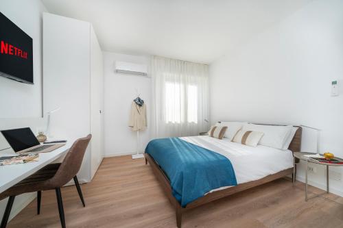 Un dormitorio con una cama y un escritorio con una computadora. en Oberdan 5 Centro Storico - A Casa Tua, en Pordenone