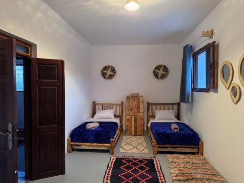two beds in a room with a door and a window at Fisherman House in Wassane