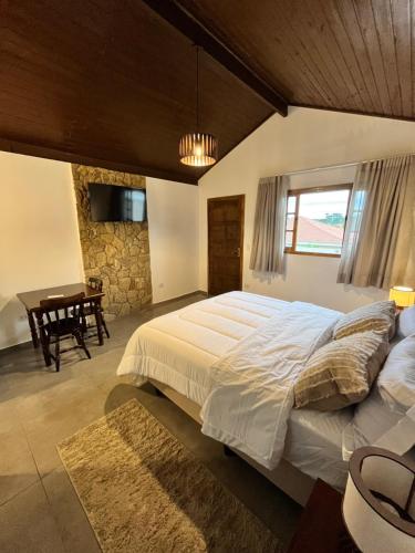 a bedroom with a large bed and a table at Recanto Góes Machado, quarto Gabi in São Roque