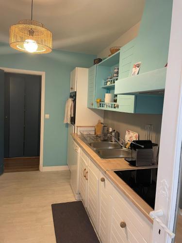 une cuisine avec des armoires bleues et un évier dans l'établissement Maison Vivaldi pour 6 pers Andernos les Bains, à Andernos-les-Bains