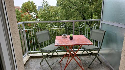 d'une table rouge et de deux chaises sur un balcon. dans l'établissement T1 - métro B François verdier, à Toulouse