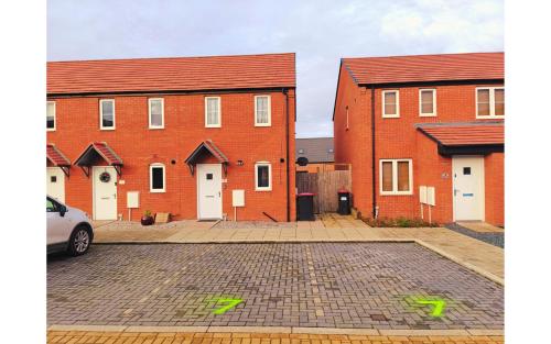 eine Gruppe roter Backsteinhäuser auf einem Parkplatz in der Unterkunft Barn Fold House with Parking, Garden, Wi-Fi in Telford