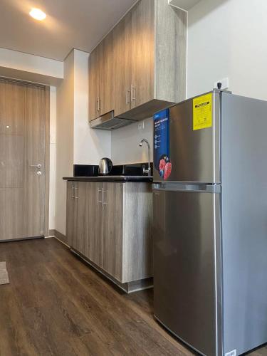 a kitchen with a stainless steel refrigerator and wooden cabinets at La Chicka Staycation in Coast Residences in Manila