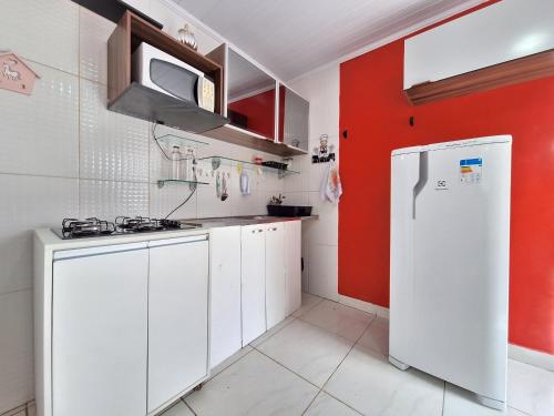 a kitchen with white cabinets and a red wall at Casa em Stella Maris, 1km da praia - Excelente localização! in Salvador