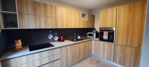 a kitchen with wooden cabinets and a sink and a microwave at Appartamento BUCANEVE in Pieve Tesino