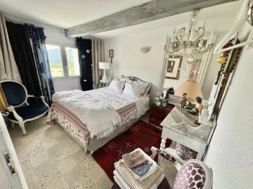 une chambre avec un lit, une chaise et un miroir dans l'établissement Les Magnolias, à Montbrun-les-Bains