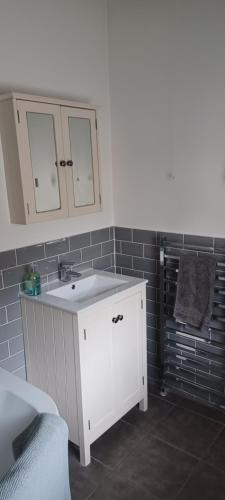 ラグビーにあるRugby town centre house close to rugby train station and rugby schoolの白いシンクとグレーのタイルを使用したバスルーム