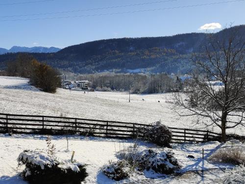 a snow covered field with a fence and trees at Wellness- HotTub & Sauna- Pet Friendly- Hiking in Keutschach am See