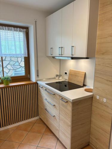 a kitchen with white cabinets and a sink and a window at Obereggen - Anna in Eggen