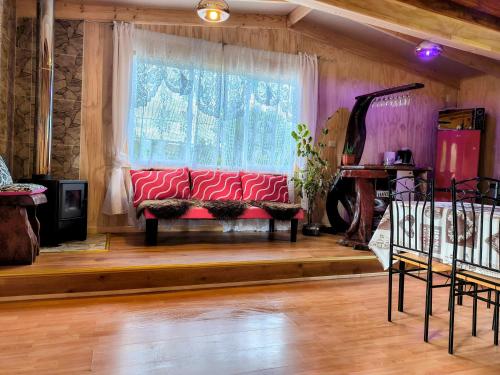 a living room with a red couch in front of a window at Cabañas Lago Llanquihue in Llanquihue