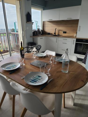 une table en bois avec des assiettes et des verres à vin dessus dans l'établissement Le Front de Mer, à Saint-Jean-de-Monts