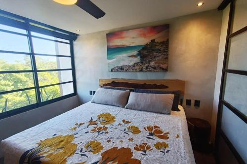 トゥルムにあるLuxury Loft in Aldea Zama with Rooftop Poolのベッドと壁に絵が飾られた寝室