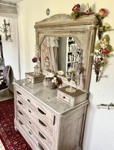 - une commode avec un miroir sur un mur dans l'établissement Les Magnolias, à Montbrun-les-Bains