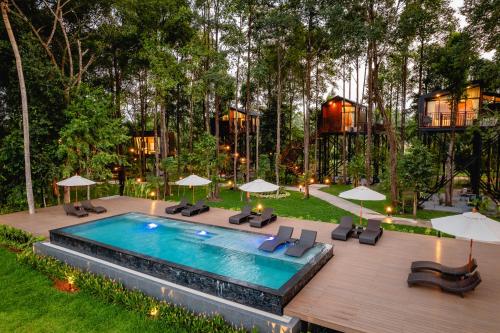 a pool with chairs and umbrellas in a yard at High Tree Resort, Krabi in Ao Nam Mao