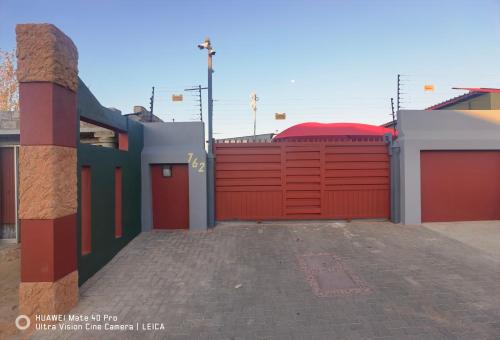a garage with a red gate and a driveway at Fresh Ideas GuestHouse in Soshanguve