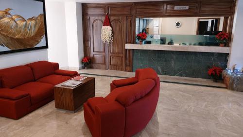 a living room with two red chairs and a table at Hotel Real Del Sol - Zona Expo Industrial in Guadalajara