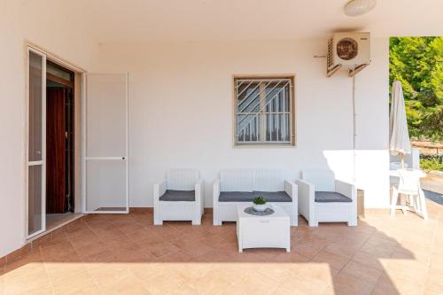 a patio with white chairs and a table and a window at Villa Flaminio in Specchiolla 