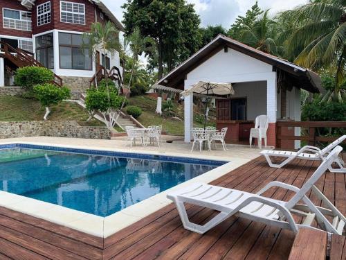 a swimming pool with two chairs and an umbrella at Casa Carabela, Omoa, Cortes in Omoa