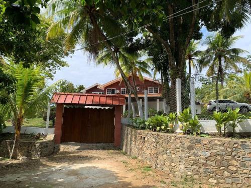 a house with a garage and a stone wall at Casa Carabela, Omoa, Cortes in Omoa