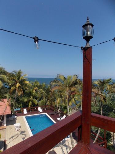 a lamp on a balcony with a pool and palm trees at Casa Carabela, Omoa, Cortes in Omoa