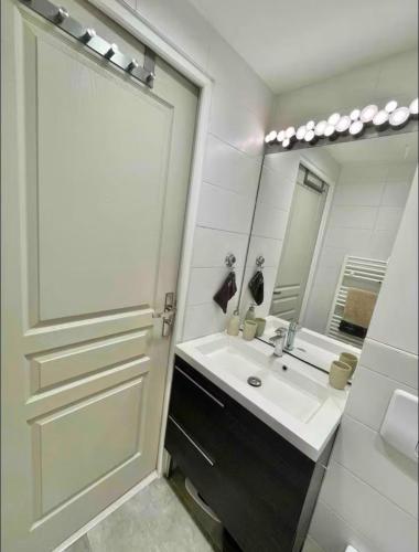 une salle de bain avec un lavabo et un grand miroir dans l'établissement Chambre à 10 min de Paris, à Argenteuil