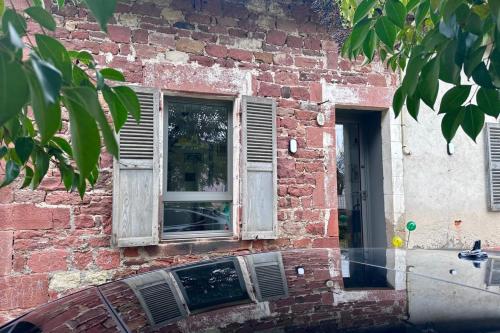 un bâtiment en briques avec une fenêtre et une voiture devant dans l'établissement Maison de Marie - T2 ClimTerrasse - Meyssac Bourg, à Meyssac