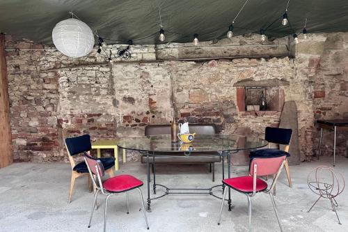 - une table et des chaises dans une pièce dotée d'un mur en briques dans l'établissement Maison de Marie - T2 ClimTerrasse - Meyssac Bourg, à Meyssac