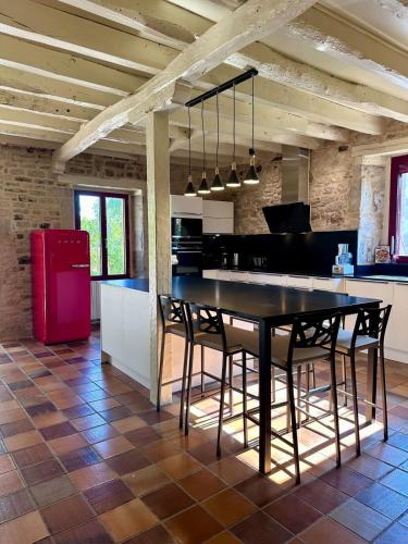 Il comprend une cuisine équipée d'une table et de chaises noires ainsi que d'un réfrigérateur rouge. dans l'établissement Maison d'Antan - PiscineJardinClim - Bourg de Cuzance, à Cuzance