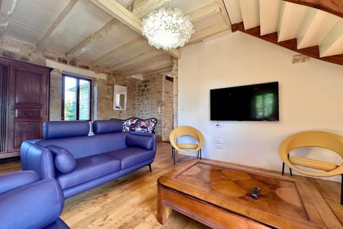 un salon avec un canapé bleu et une télévision dans l'établissement Maison d'Antan - PiscineJardinClim - Bourg de Cuzance, à Cuzance