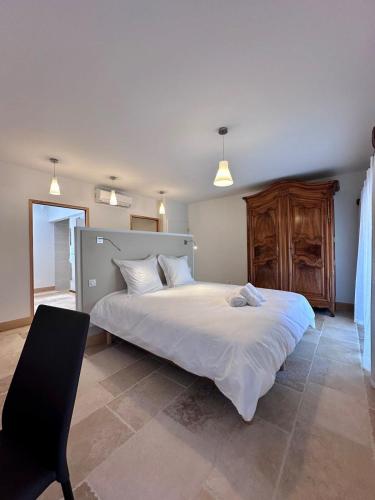 une chambre avec un grand lit blanc et une chaise dans l'établissement Grange d'Antan -JacuzziPiscineClim -Cuzance, à Cuzance