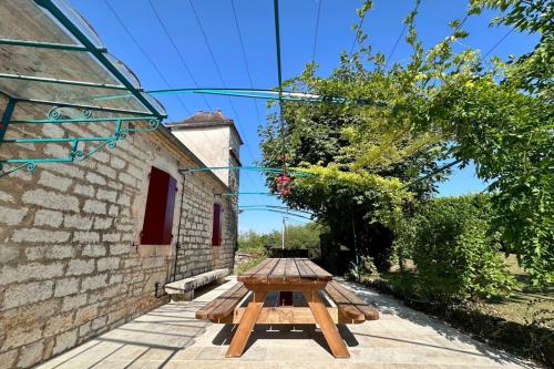 a wooden picnic table in front of a building at Maison d'Antan - PiscineJardinClim - Bourg de Cuzance in Cuzance